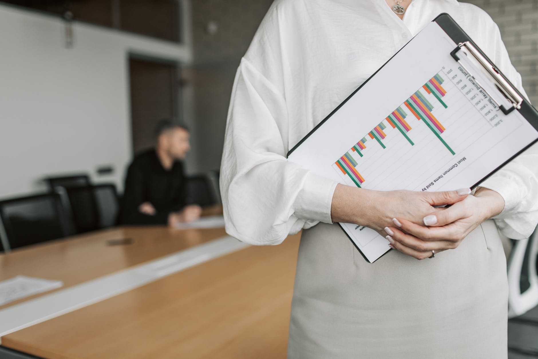 person in white long sleeve shirt holding a clipboard with statistics